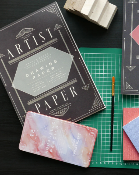 Artist drawing paper set with a cutting mat and tools on a dark surface