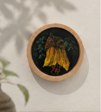 Small round painting of a bunch of bananas in a wooden frame on a light background
